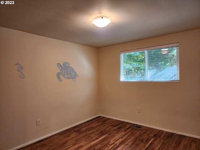 unfurnished room featuring visible vents, baseboards, and dark wood-style floors