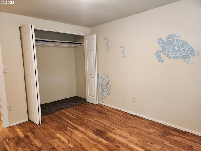 unfurnished bedroom with a closet, baseboards, and wood finished floors