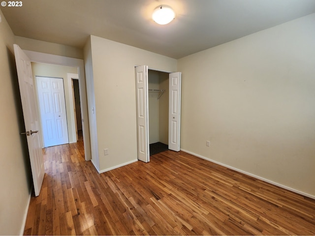 unfurnished bedroom with baseboards, a closet, and wood finished floors