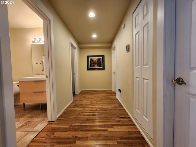 hall with wood finished floors, baseboards, and recessed lighting
