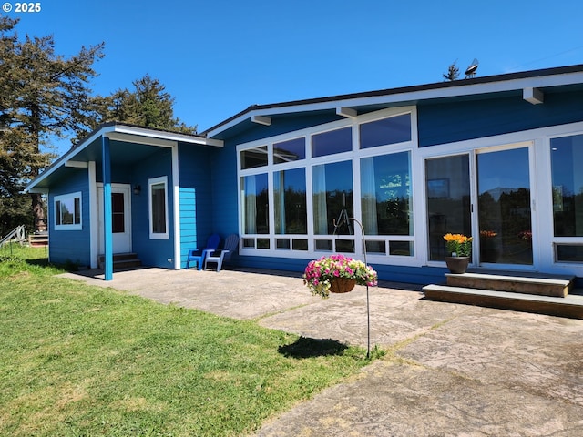 back of property featuring a lawn, entry steps, and a patio