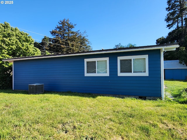 view of side of property featuring a lawn and central AC