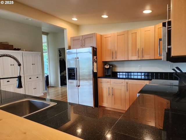 kitchen with dark countertops, stainless steel fridge, light brown cabinets, and recessed lighting