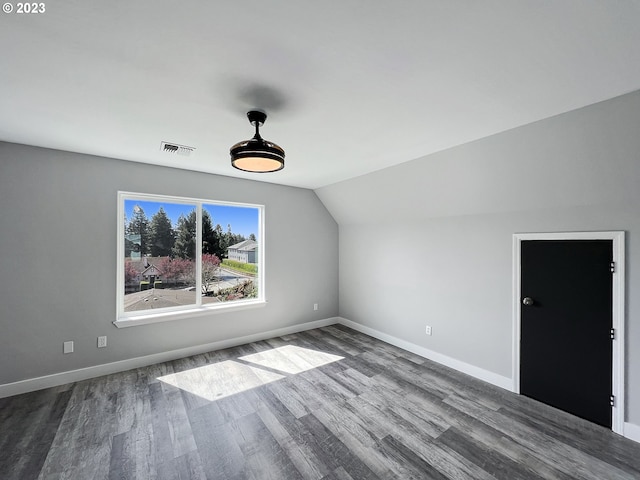 empty room featuring vaulted ceiling and dark hardwood / wood-style flooring