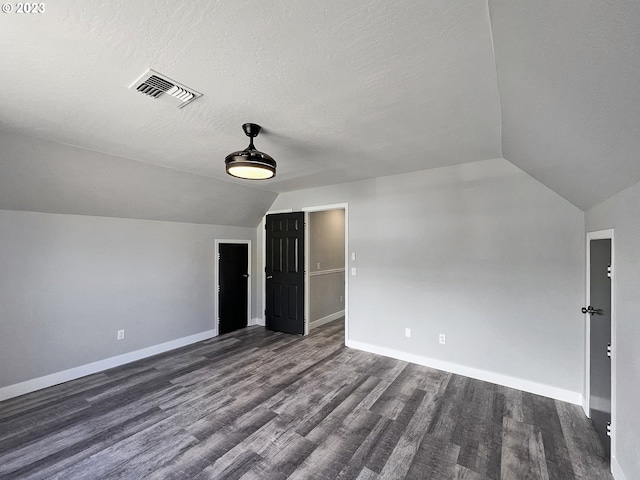 additional living space with lofted ceiling, a textured ceiling, and dark hardwood / wood-style floors