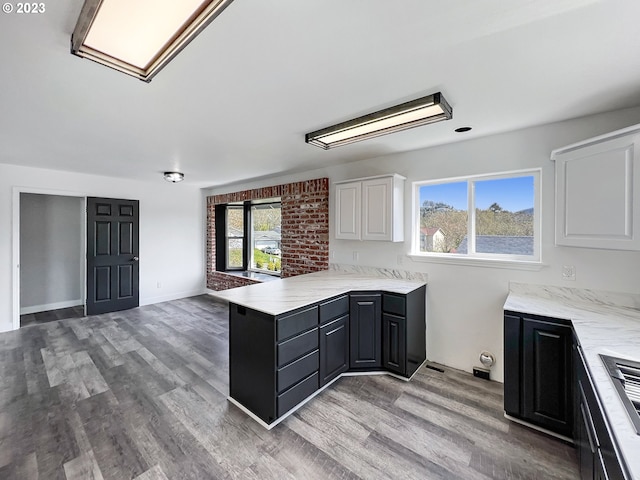 kitchen featuring kitchen peninsula, white cabinetry, light stone countertops, and light wood-type flooring