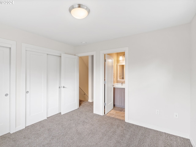 unfurnished bedroom featuring a closet, connected bathroom, and light colored carpet