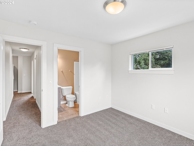 unfurnished bedroom featuring light carpet and ensuite bath