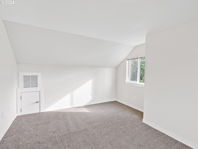 bonus room with lofted ceiling and dark colored carpet