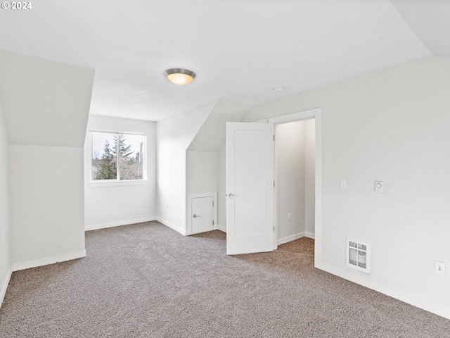 bonus room with lofted ceiling and dark colored carpet