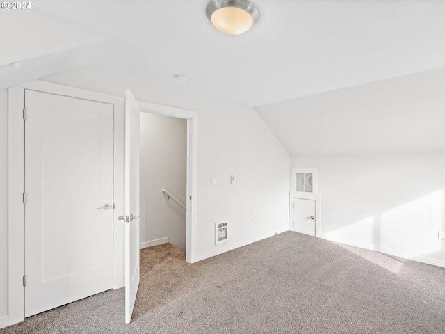 additional living space featuring light carpet and vaulted ceiling