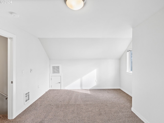 bonus room with dark carpet and vaulted ceiling