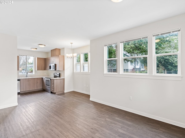 kitchen with decorative light fixtures, light brown cabinetry, dark wood-type flooring, appliances with stainless steel finishes, and an inviting chandelier