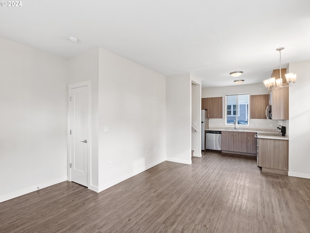 kitchen with decorative light fixtures, dark hardwood / wood-style floors, a notable chandelier, appliances with stainless steel finishes, and sink