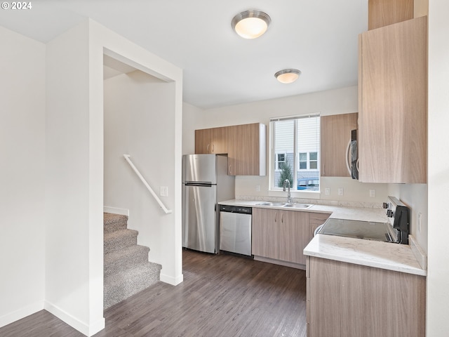 kitchen with appliances with stainless steel finishes, light brown cabinetry, dark wood-type flooring, sink, and light stone countertops