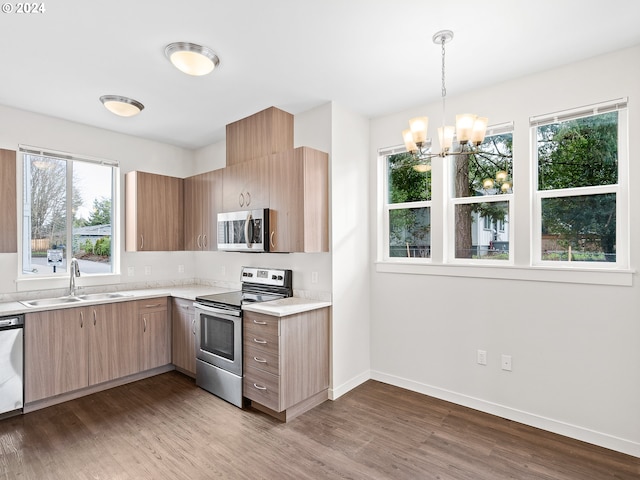 kitchen featuring appliances with stainless steel finishes, decorative light fixtures, sink, a chandelier, and dark hardwood / wood-style floors