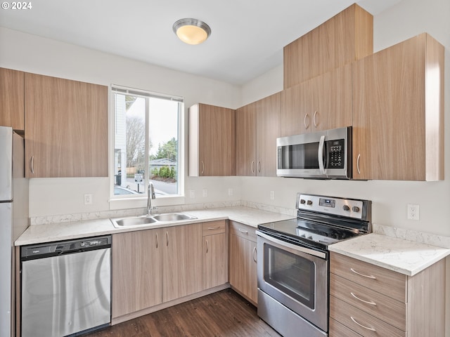 kitchen with light brown cabinetry, sink, stainless steel appliances, dark wood-type flooring, and light stone countertops