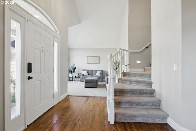 entryway featuring stairs, dark wood-type flooring, a high ceiling, and baseboards