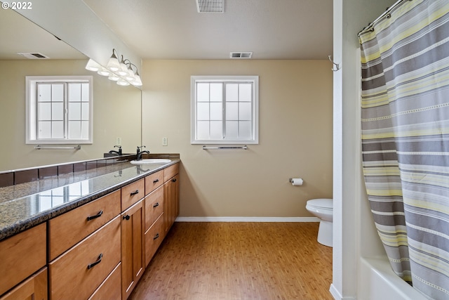 full bathroom featuring toilet, hardwood / wood-style floors, shower / tub combo with curtain, and vanity