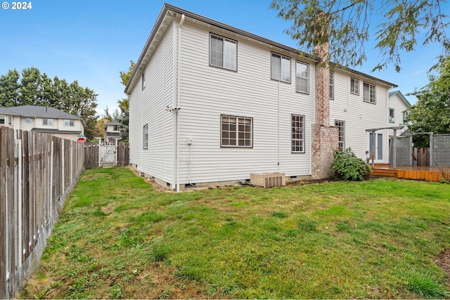 rear view of property with a deck, a yard, and central AC unit