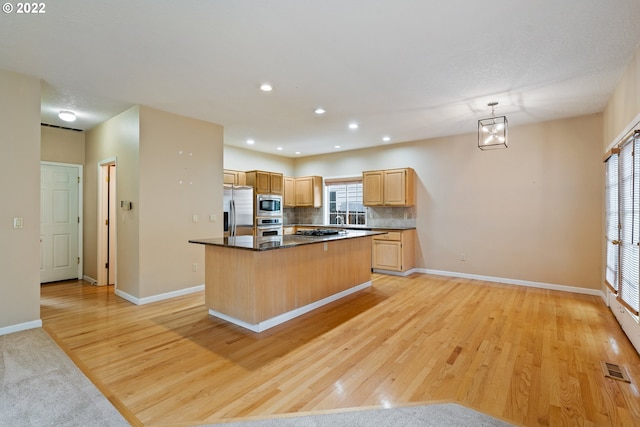 kitchen featuring a kitchen island, appliances with stainless steel finishes, and light wood-type flooring