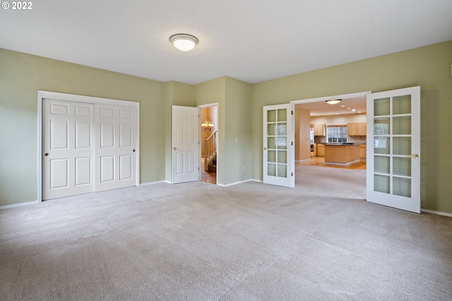 unfurnished bedroom featuring a closet, french doors, and light colored carpet