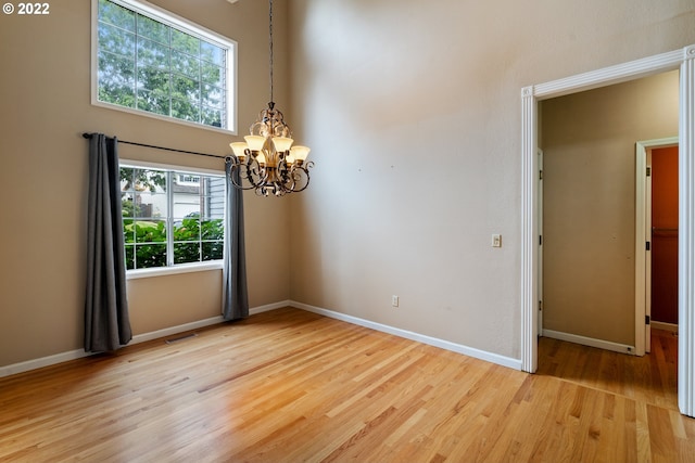 empty room featuring light hardwood / wood-style flooring and an inviting chandelier