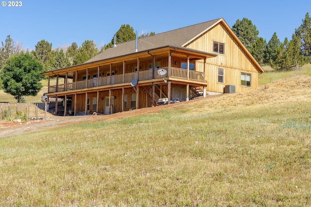 rear view of house featuring a balcony, central AC unit, and a yard