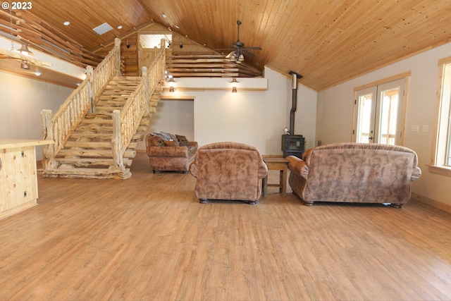 living room with light hardwood / wood-style floors, wooden ceiling, ceiling fan, french doors, and a wood stove