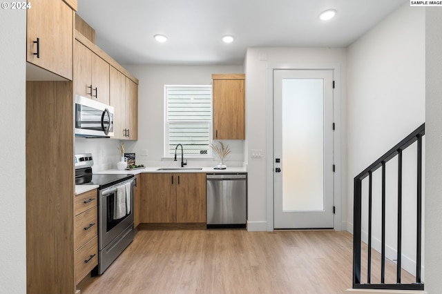 kitchen with stainless steel appliances, sink, and light hardwood / wood-style flooring