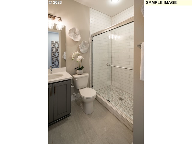 bathroom with toilet, tile floors, a shower with shower door, and vanity