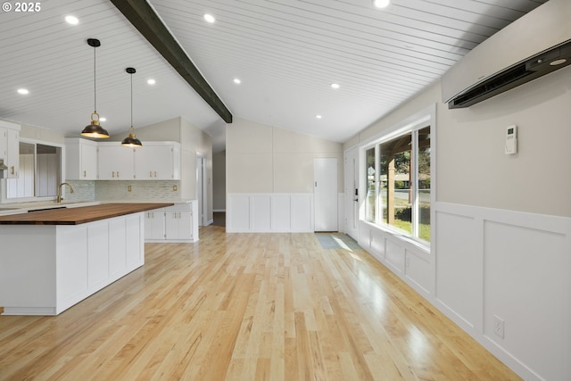 kitchen with white cabinets, lofted ceiling with beams, wood counters, light wood-type flooring, and backsplash