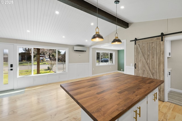 kitchen with a wealth of natural light, light wood-style flooring, a barn door, an AC wall unit, and butcher block countertops