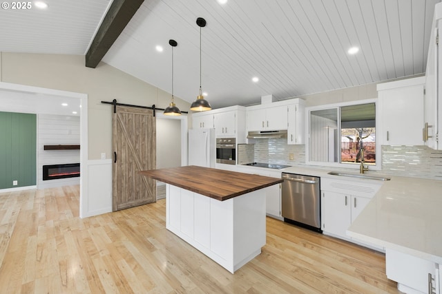 kitchen featuring a barn door, light wood-style flooring, butcher block counters, a sink, and appliances with stainless steel finishes