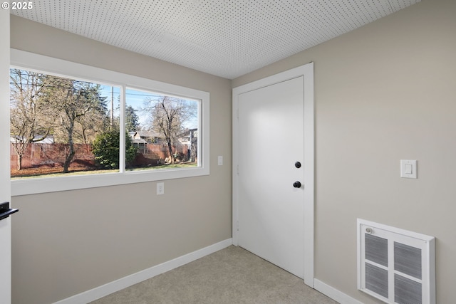 interior space with baseboards, visible vents, and light colored carpet