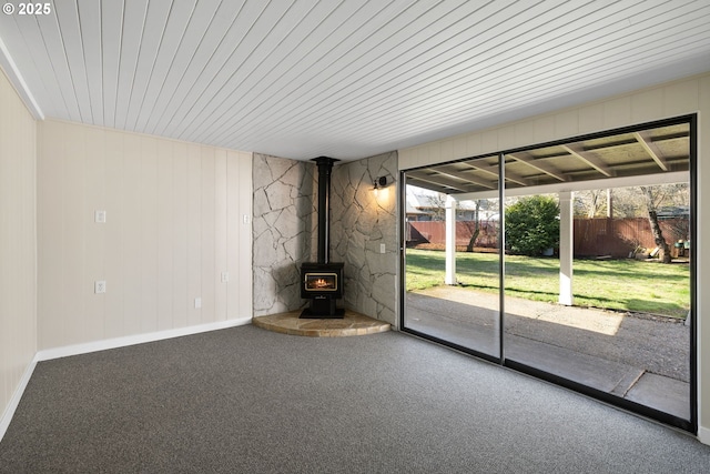 unfurnished living room featuring carpet floors and a wood stove