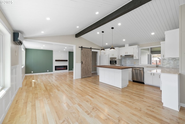 kitchen with a barn door, a wall unit AC, a kitchen island, appliances with stainless steel finishes, and wooden counters