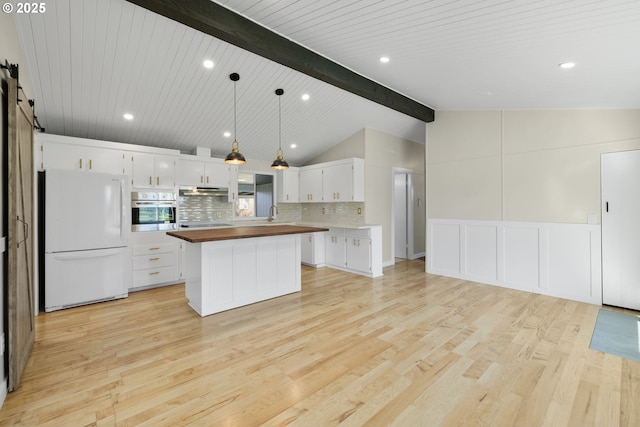 kitchen featuring a barn door, oven, butcher block counters, light wood-type flooring, and freestanding refrigerator