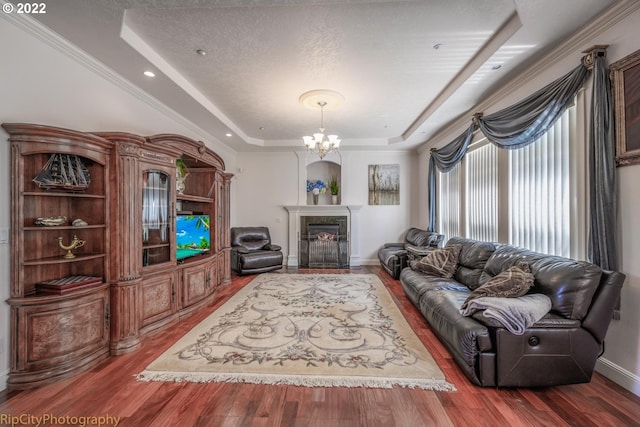 living room featuring a textured ceiling, a tray ceiling, wood-type flooring, and an inviting chandelier