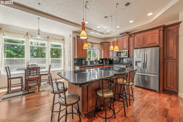 kitchen featuring backsplash, stainless steel appliances, a wealth of natural light, and a kitchen island