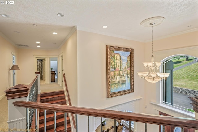 hallway with carpet flooring, a textured ceiling, a chandelier, and ornamental molding