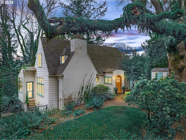 view of front of property with entry steps, roof with shingles, a chimney, and stucco siding