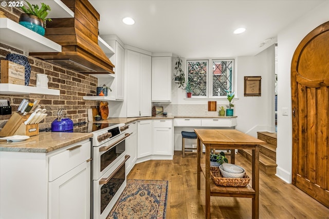 3045 SW Gaston Ave, Portland, OR 97239 - kitchen with open shelves, double oven range, backsplash, light wood-type flooring, and white cabinetry