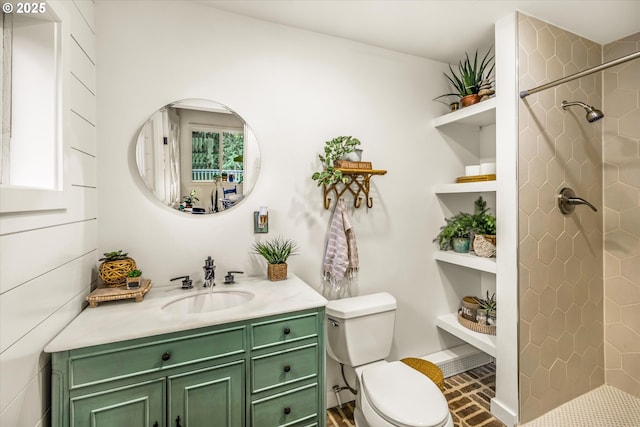 bathroom featuring brick floor, a tile shower, vanity, and toilet