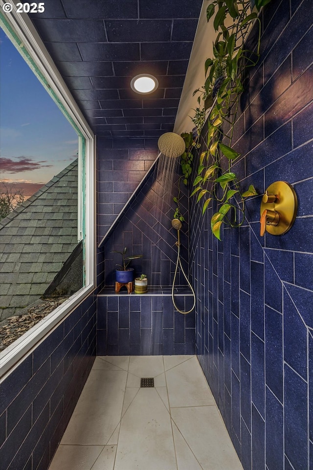 bathroom with tile patterned flooring, a tile shower, and tile walls