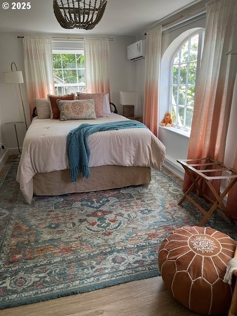 bedroom featuring wood finished floors and a wall mounted AC