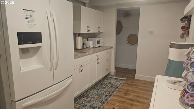 3045 SW Gaston Ave, Portland, OR 97239 - kitchen with white appliances, dark wood-style flooring, white cabinets, and baseboards