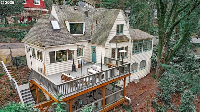 back of house featuring roof with shingles, an outdoor hangout area, a wooden deck, and stairs