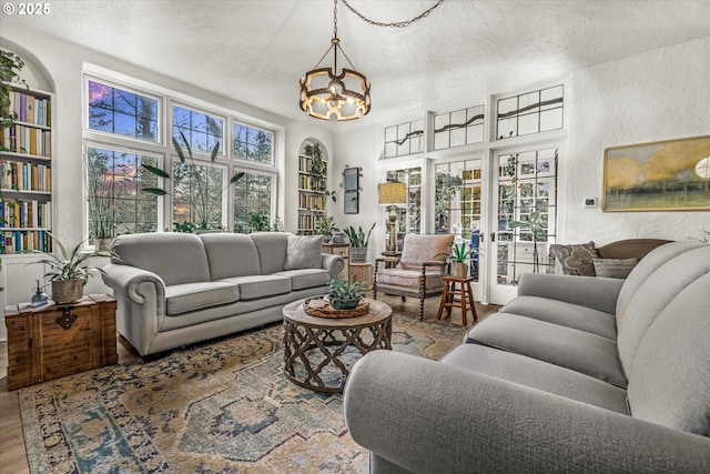 living room featuring a textured ceiling, a textured wall, wood finished floors, and a healthy amount of sunlight