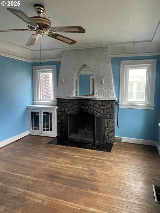 unfurnished living room with ornamental molding, hardwood / wood-style floors, ceiling fan, and a fireplace